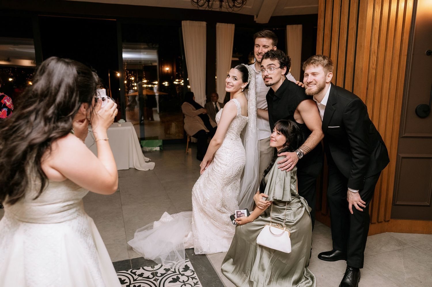Wedding celebration in an elegant wood-paneled ballroom with chandeliers and festive atmosphere.