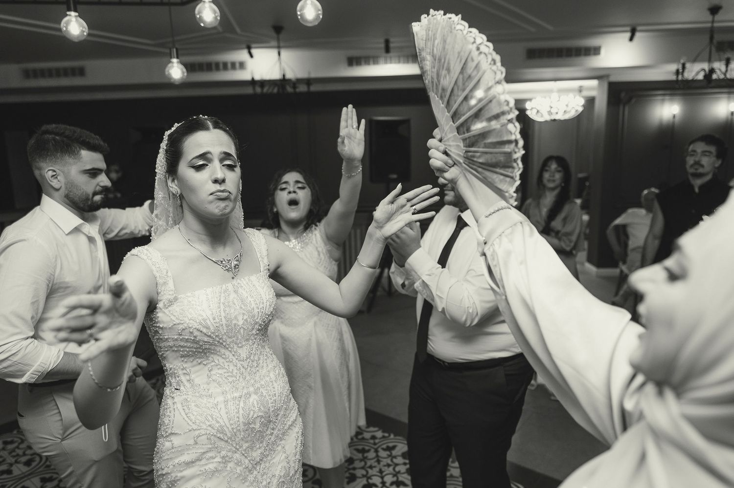 Black and white photo of wedding guests dancing enthusiastically at a reception.