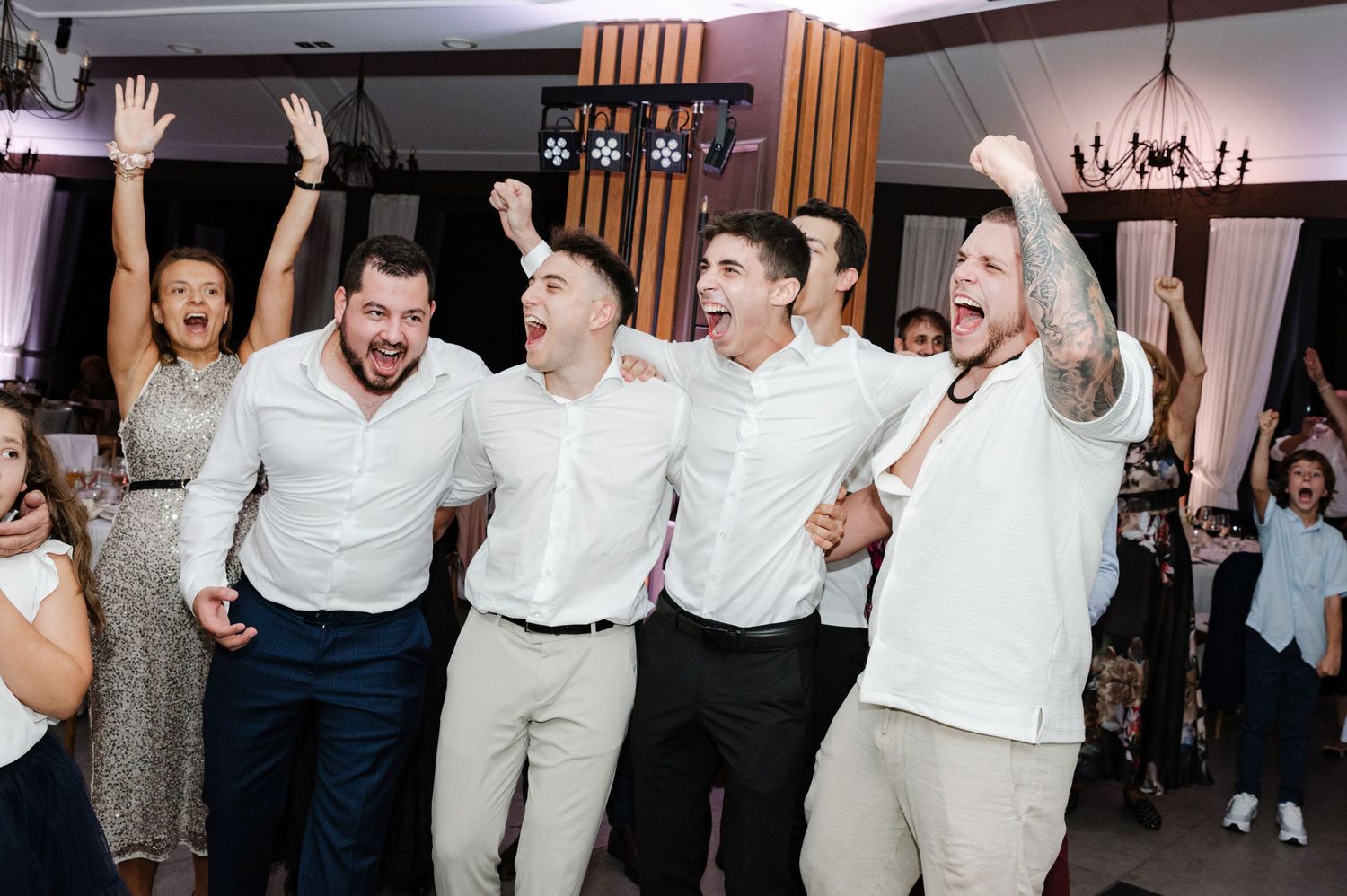 Wedding party members dancing in coordinated white and navy outfits at reception.
