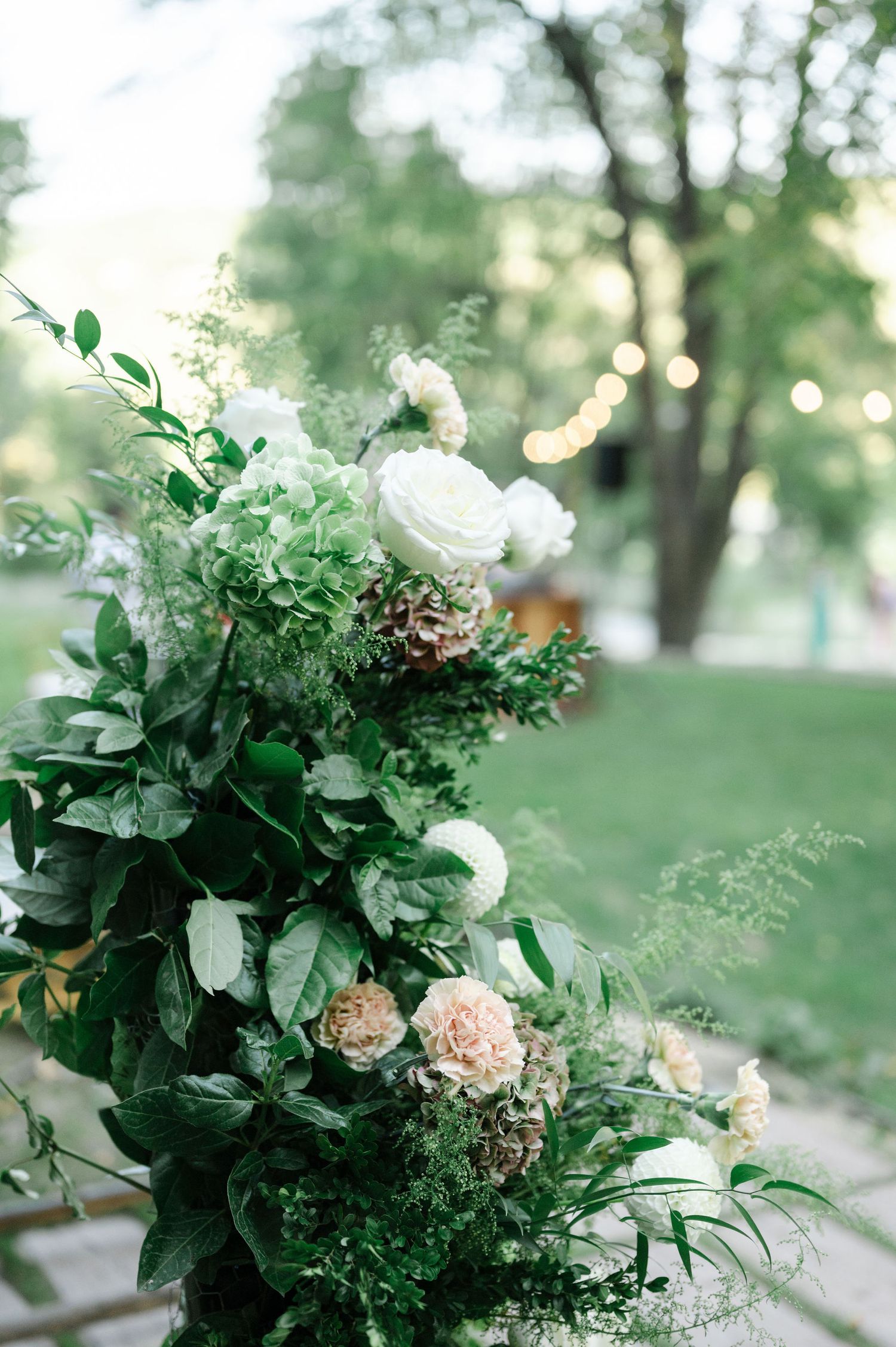 Elegant floral arrangement featuring white roses and greenery against a soft natural backdrop.
