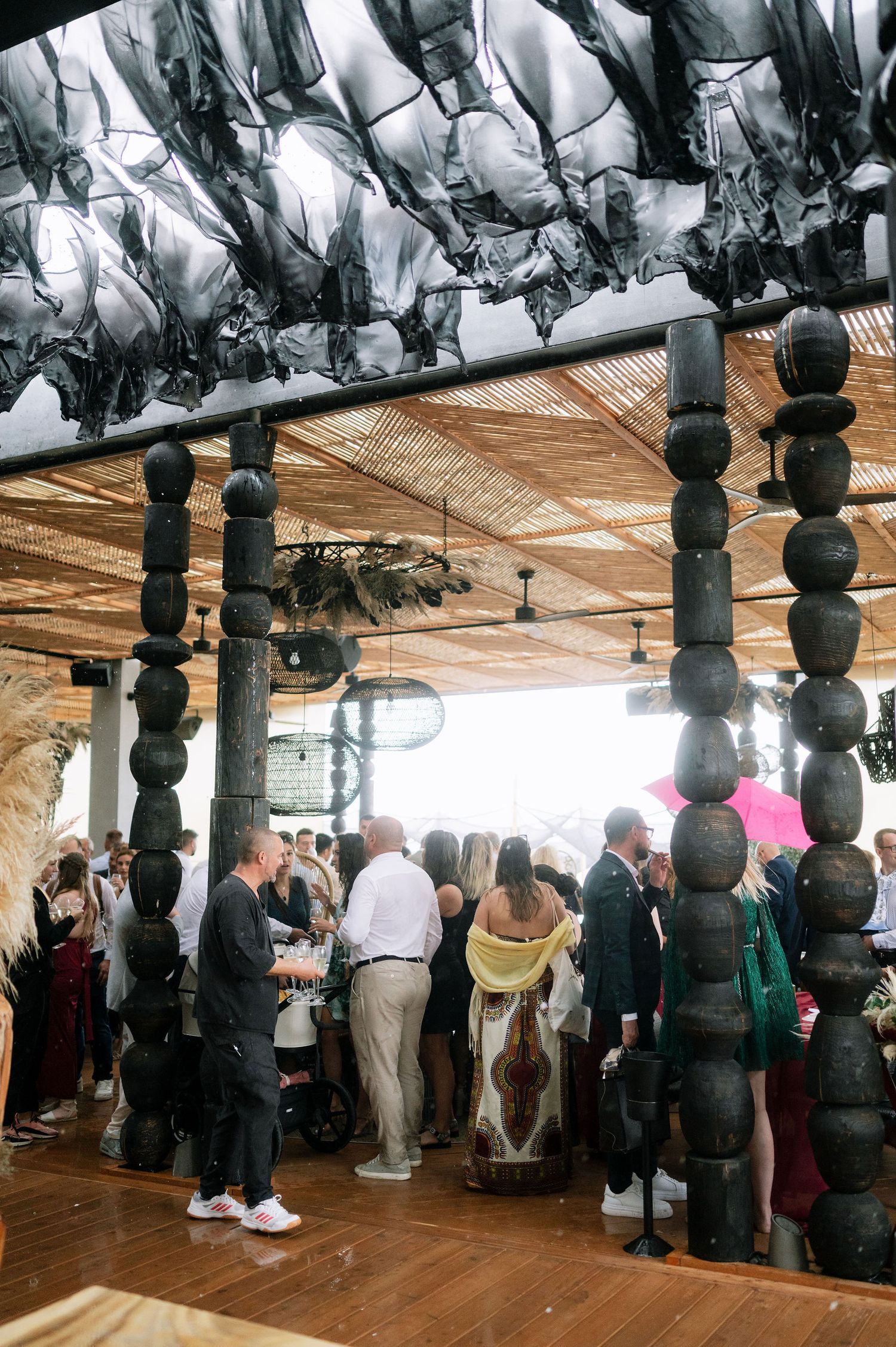 Indoor wedding reception venue with decorative hanging lights and guests mingling.