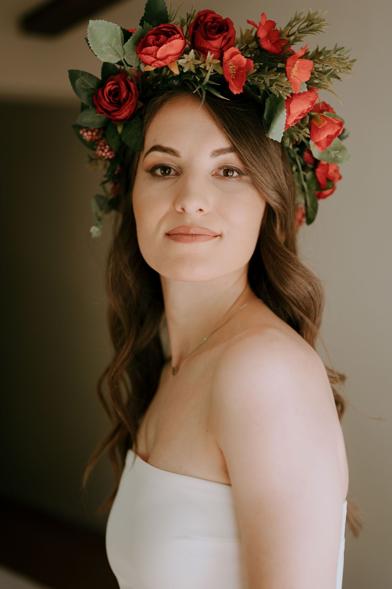 Romantic bridal portrait featuring red rose crown and classic white gown.