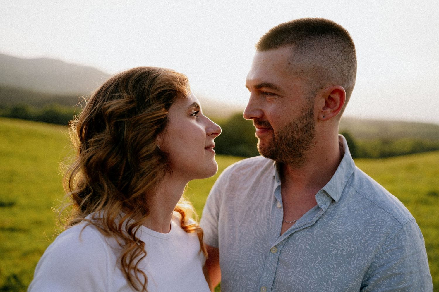 Loving couple sharing a romantic moment against rolling hills backdrop.
