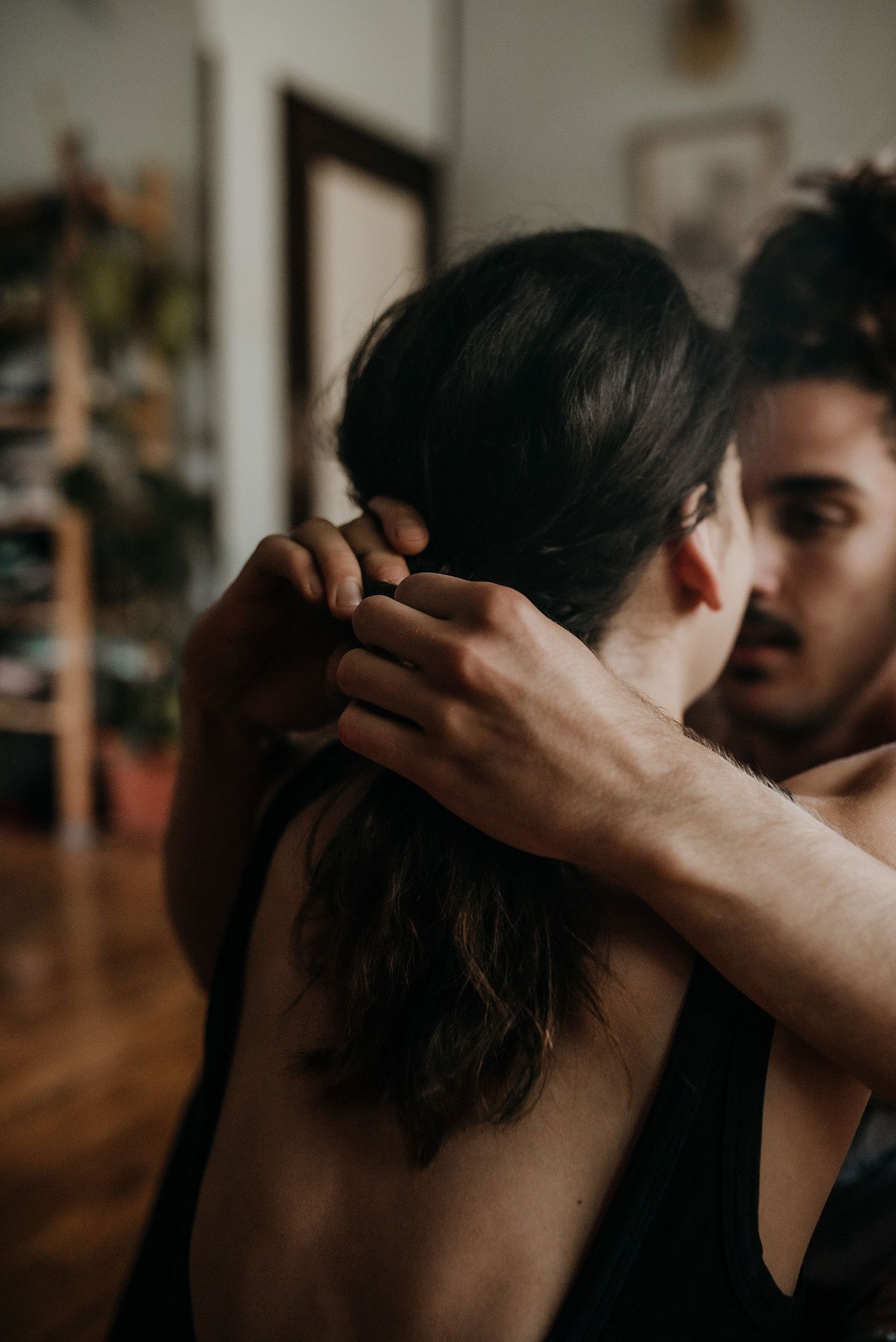 An intimate couple embraces in a dimly lit room with a warm moody atmosphere.