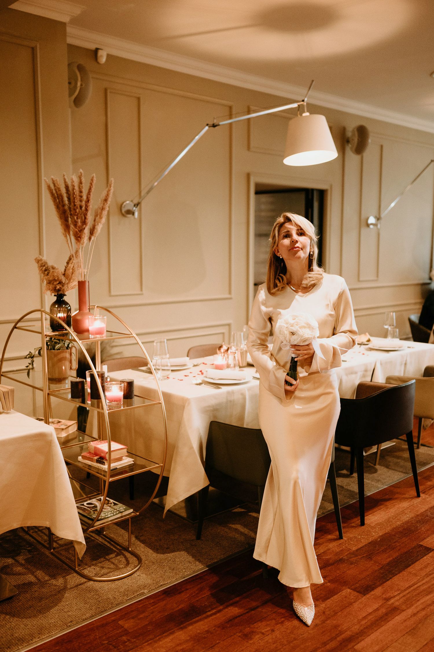 Dancing figures in flowing white dresses move through an elegantly decorated dining room.