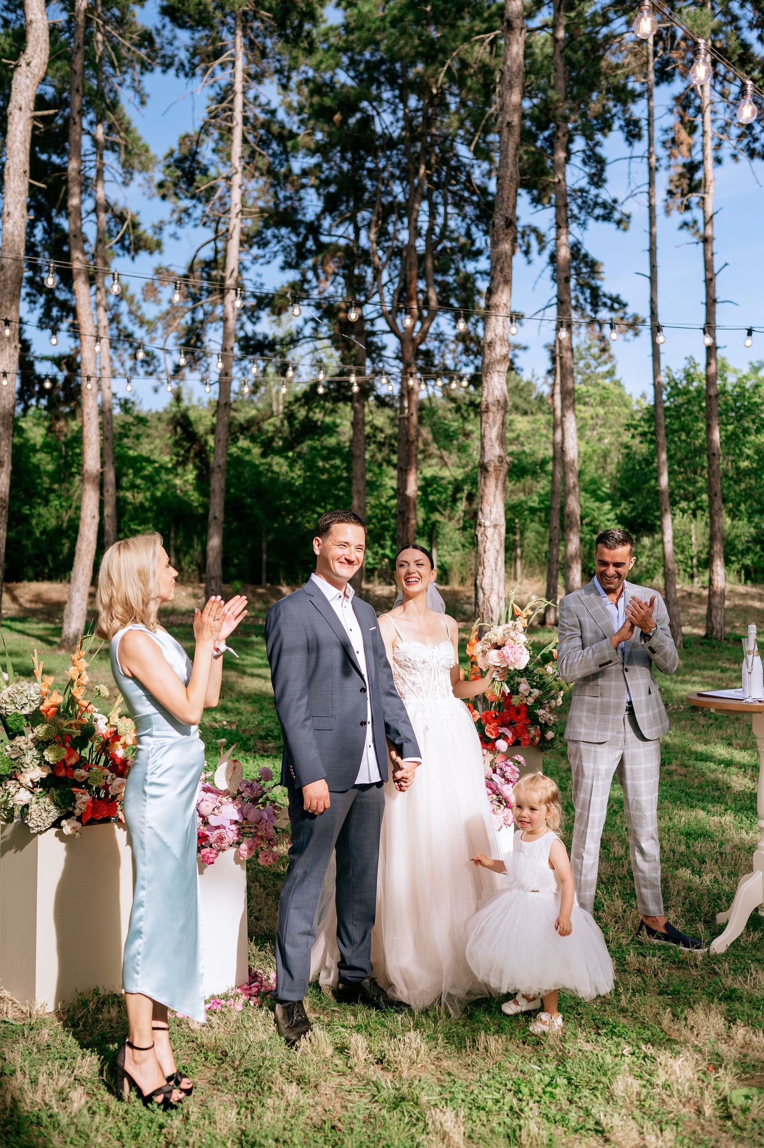 Wedding party and guests celebrate in an outdoor woodland ceremony space.