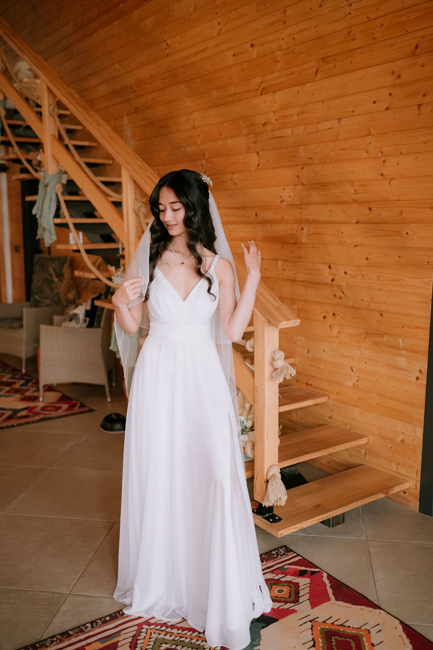 White flowing dress against wooden walls and geometric rug in rustic interior.
