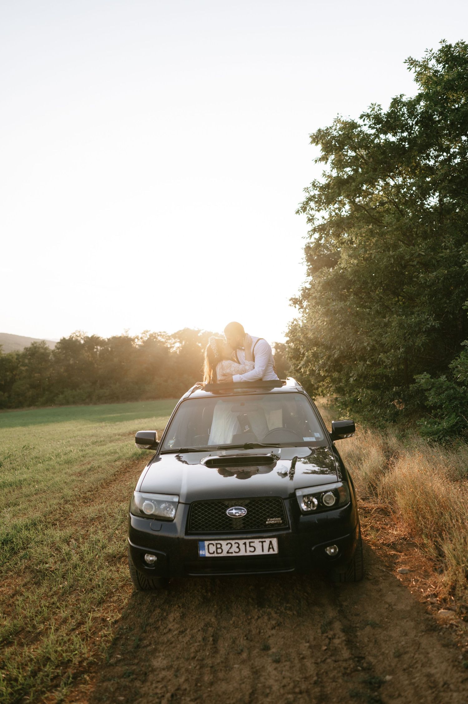 A black Subaru vehicle positioned on a rural path at sunset.