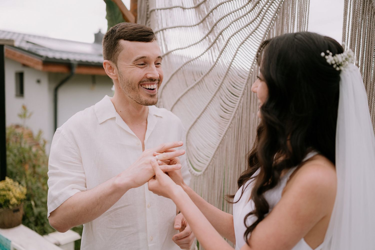 A couple in white attire sharing a joyful moment together during an outdoor photoshoot.