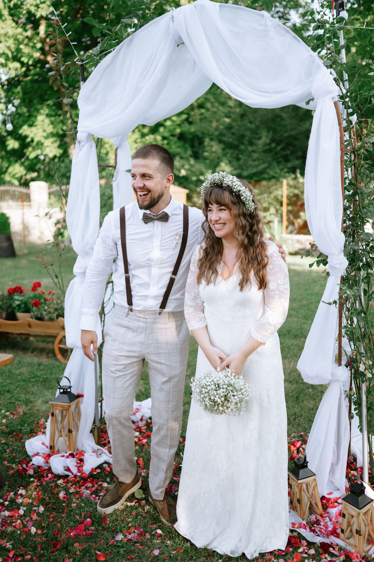 A beautiful outdoor wedding ceremony with white decor and natural garden surroundings.