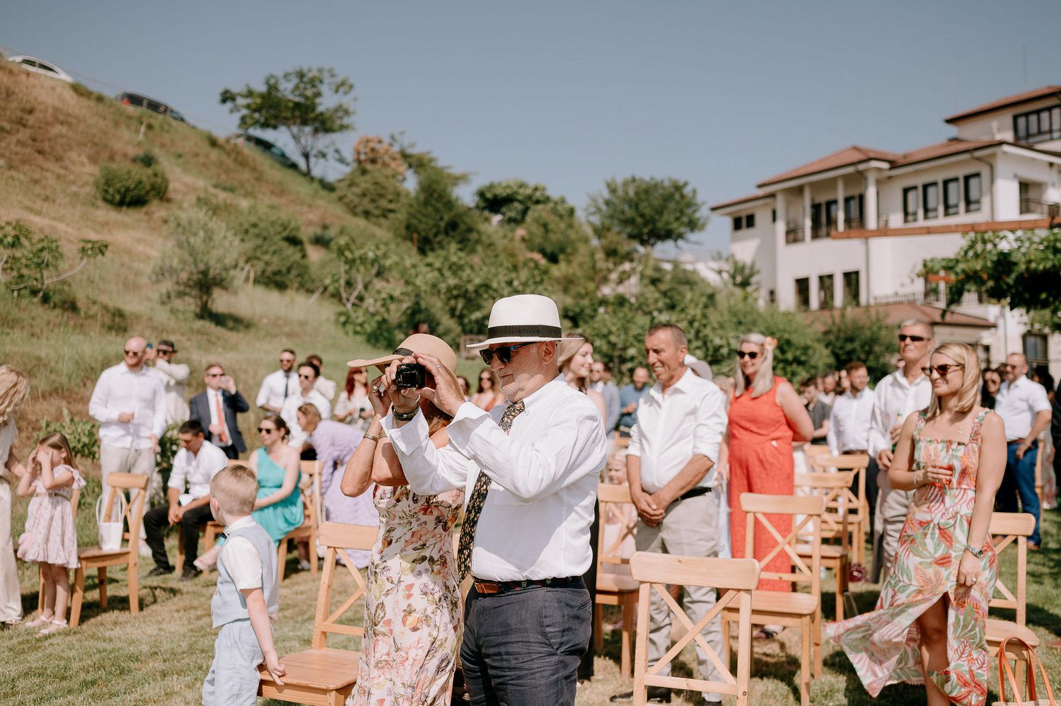 Wedding guests enjoying an outdoor celebration with chairs and decorations set up on a sunny day.