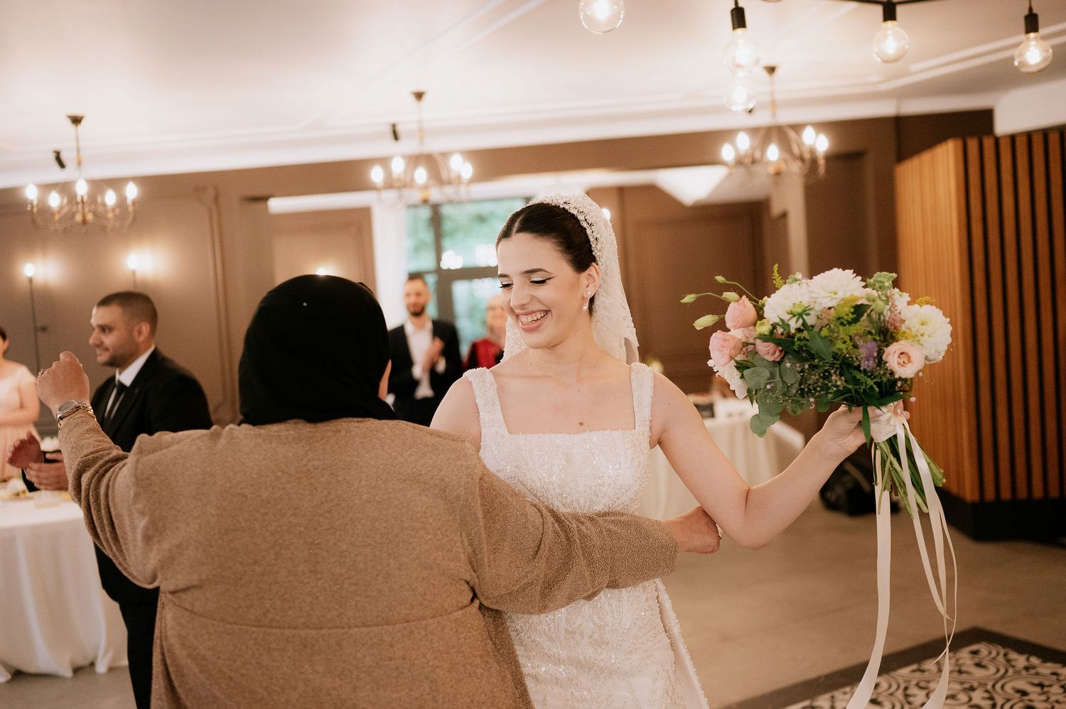 Wedding reception venue decorated with elegant chandeliers and white table settings.