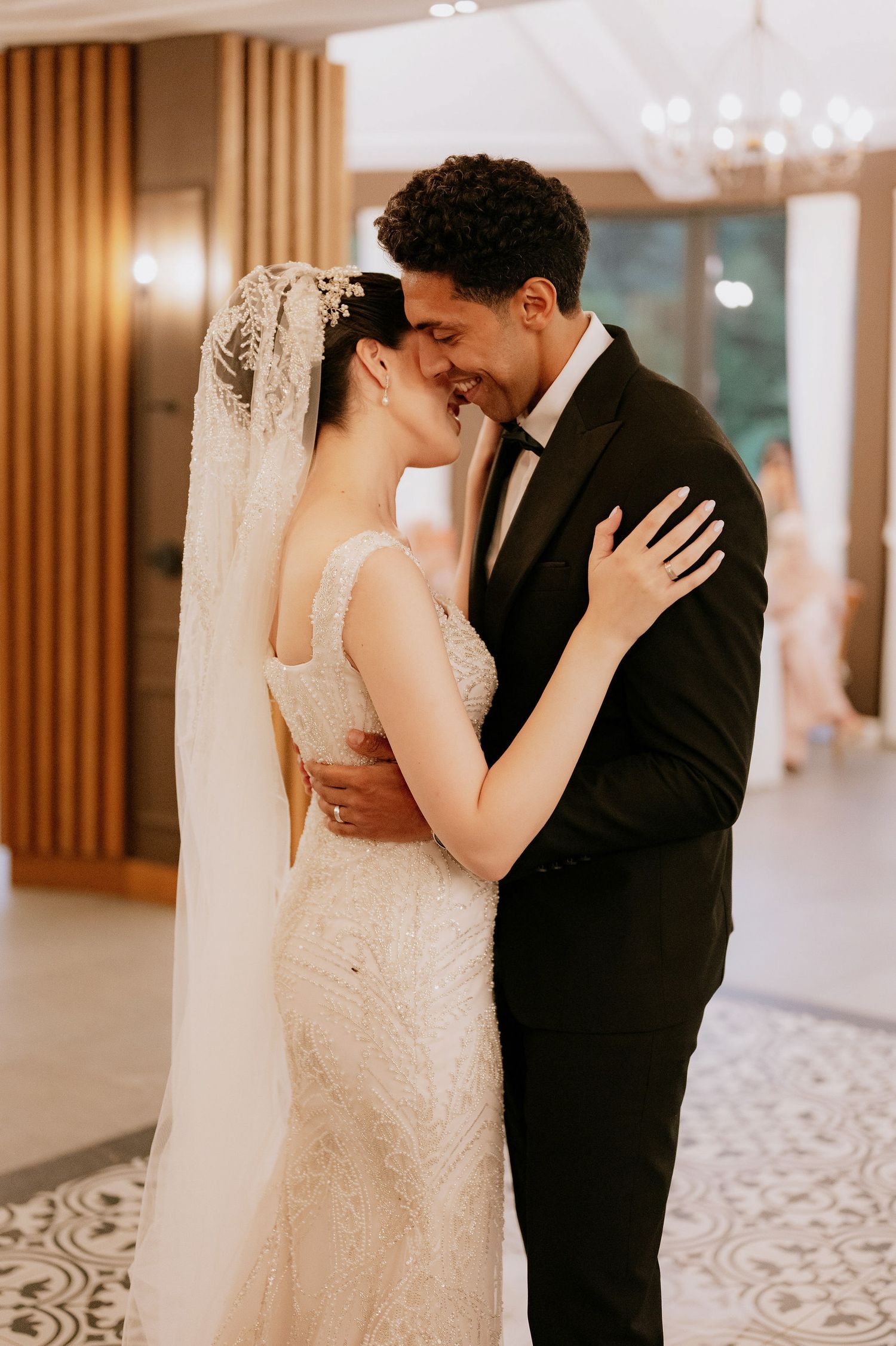 A tender moment between newlyweds during their first dance in an elegant reception space.