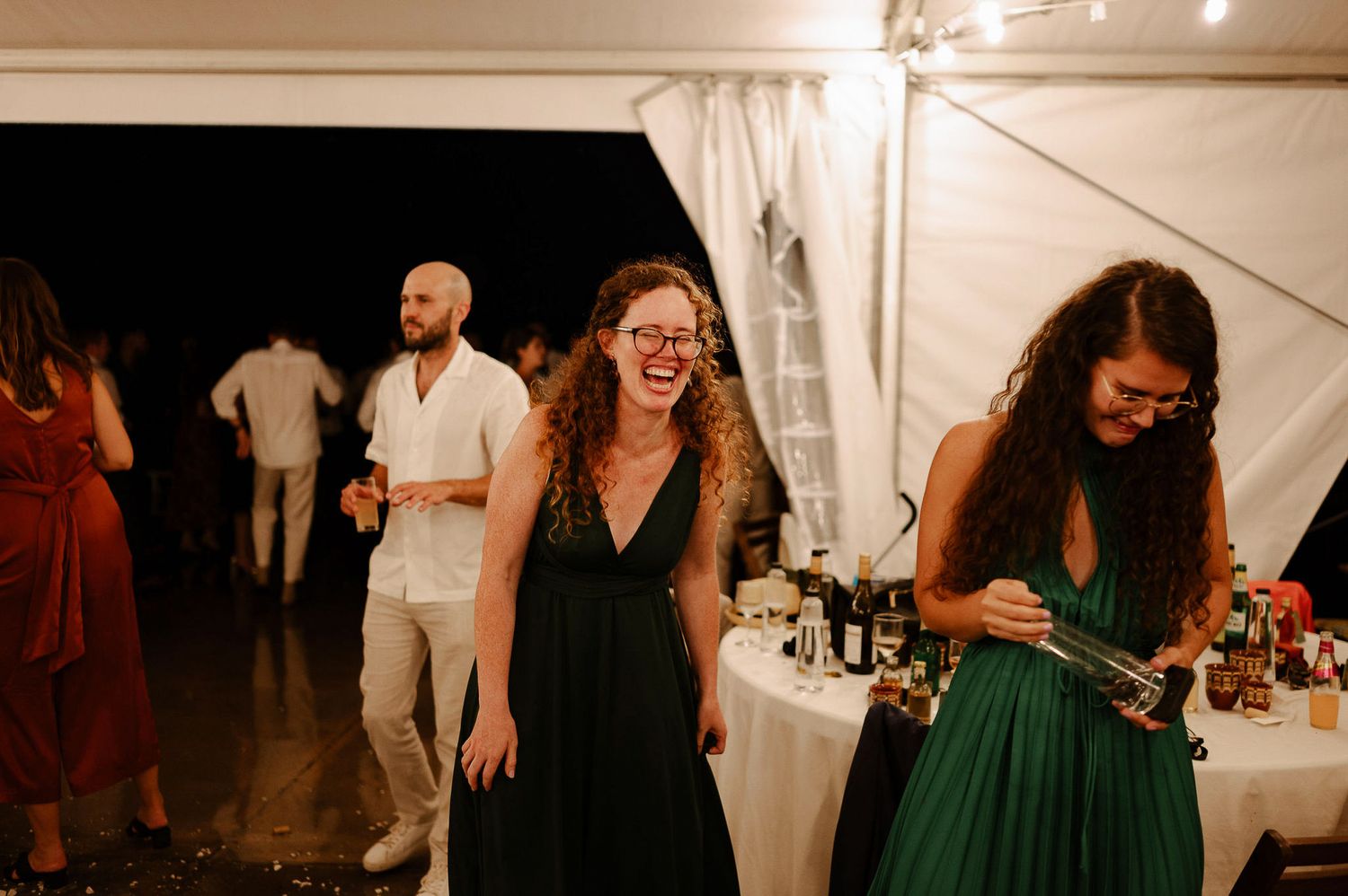 Wedding guests dance and celebrate together at an indoor reception under warm lighting.