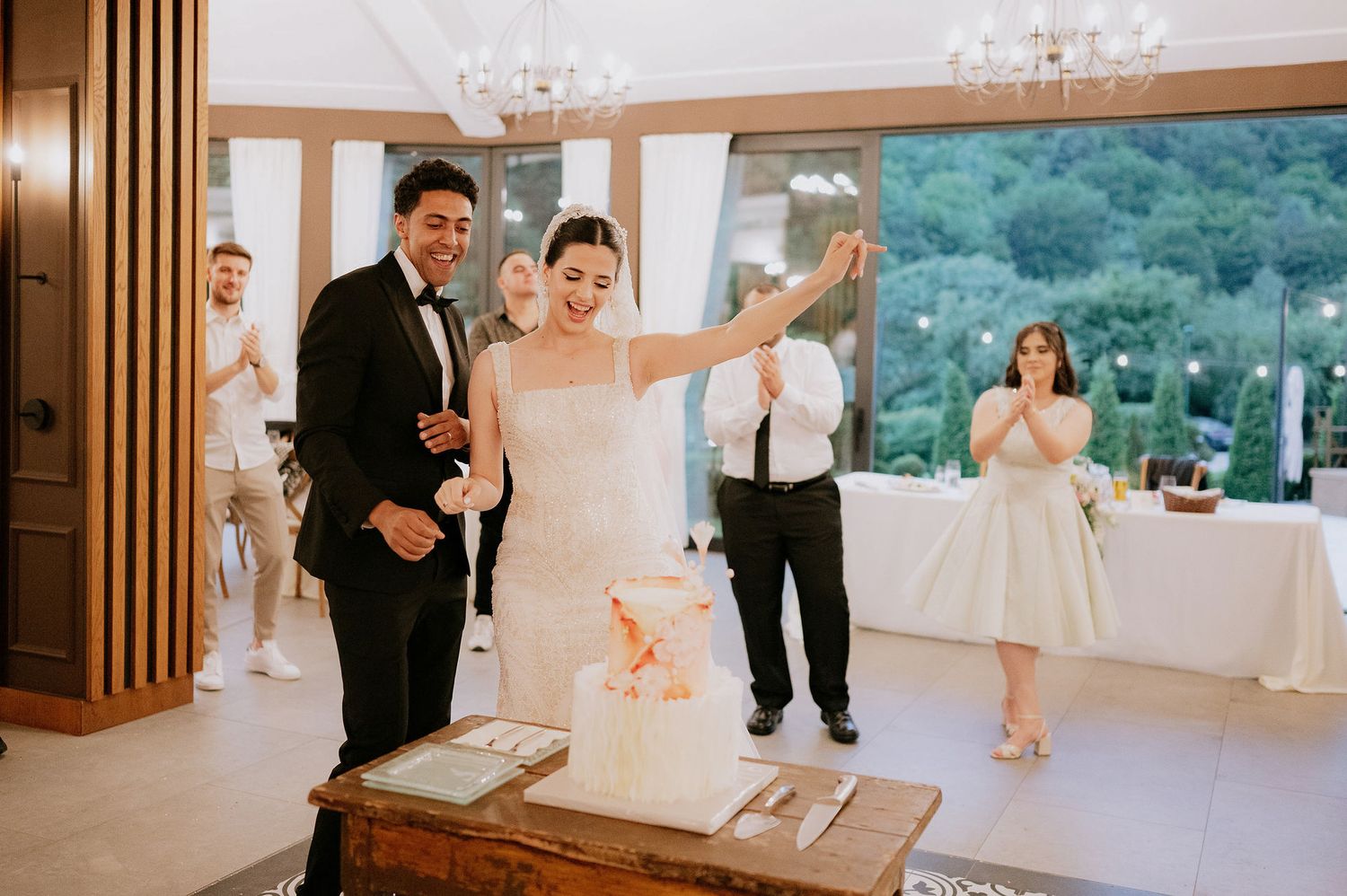 Newlyweds perform a celebratory gesture during their indoor reception.