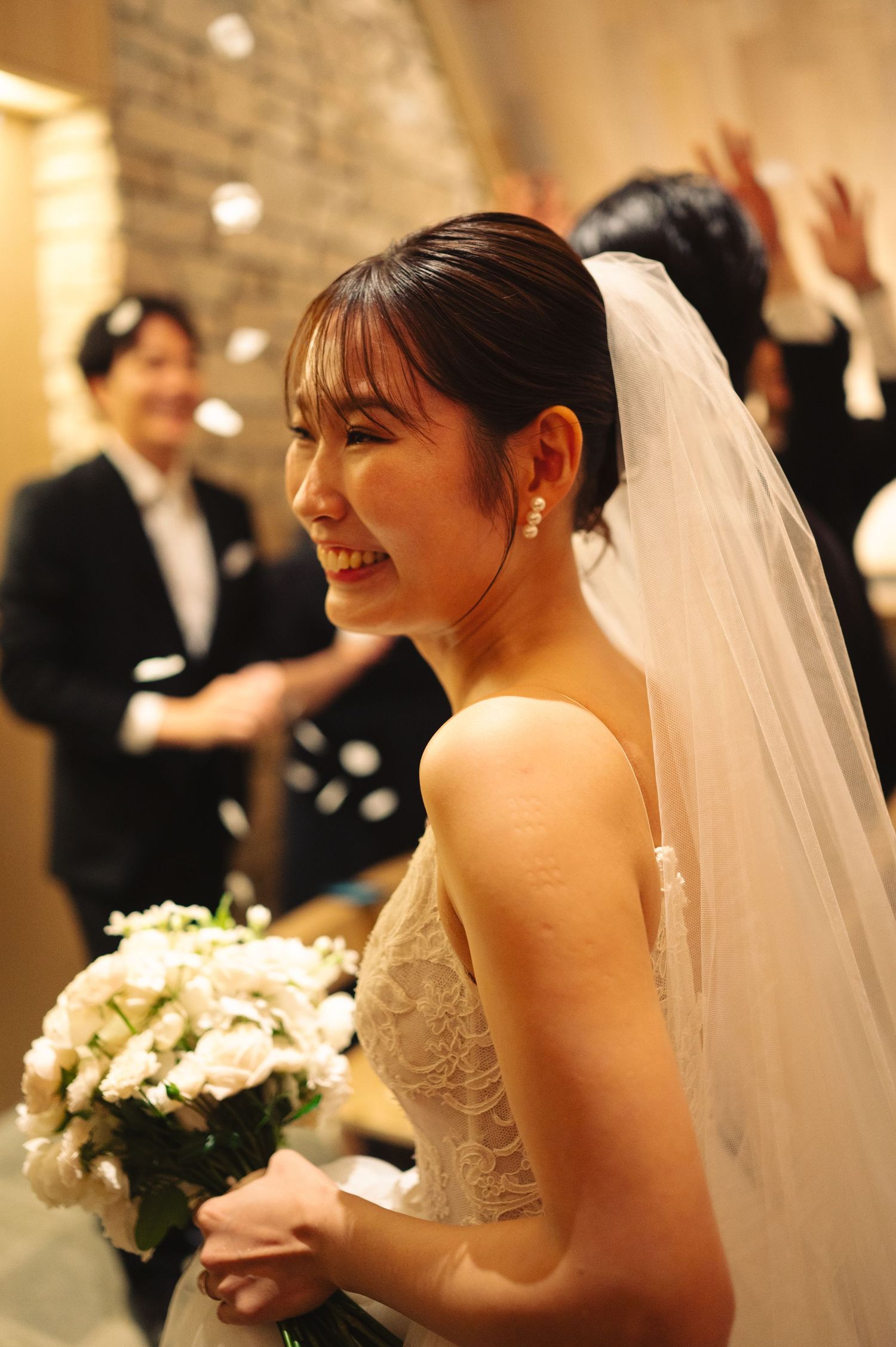 Bride holding white bouquet during wedding reception with confetti in background.