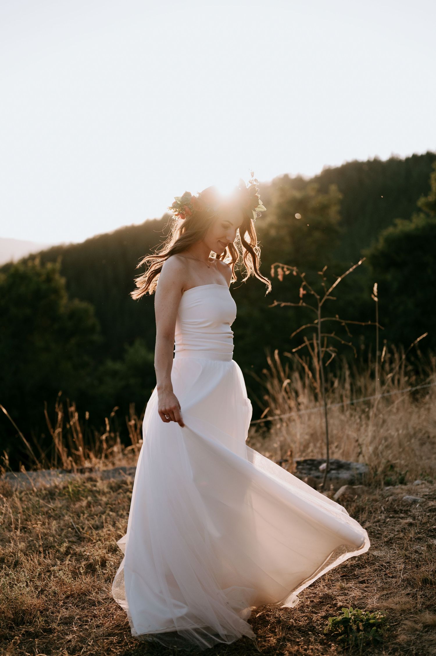A white wedding dress flows in the mountain breeze during golden hour.