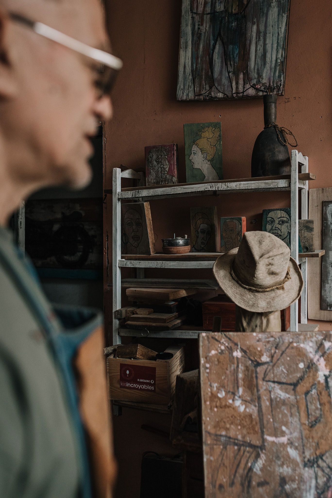 An artist's workshop with shelves and artwork visible in the warm lighting of a studio space.