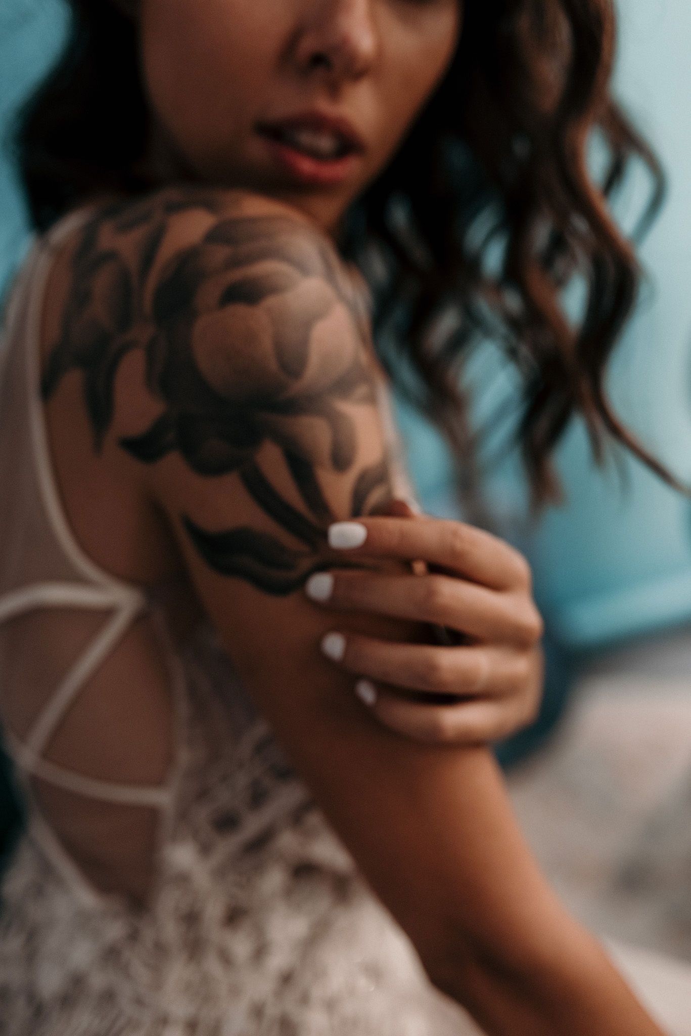 Artistic detail shot of floral tattoos and white lace dress details.
