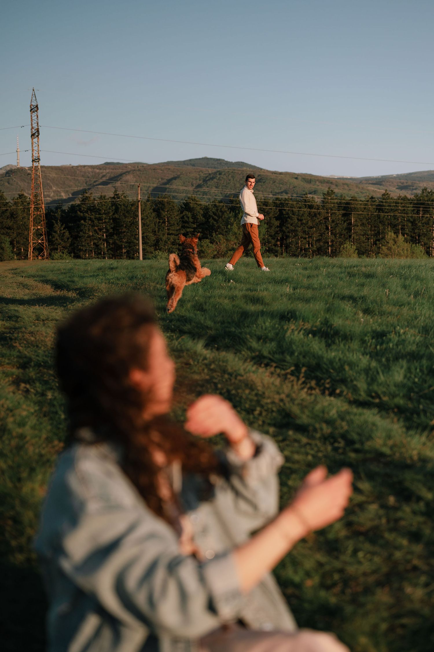People enjoying a relaxed afternoon on a grassy hillside overlooking mountains.