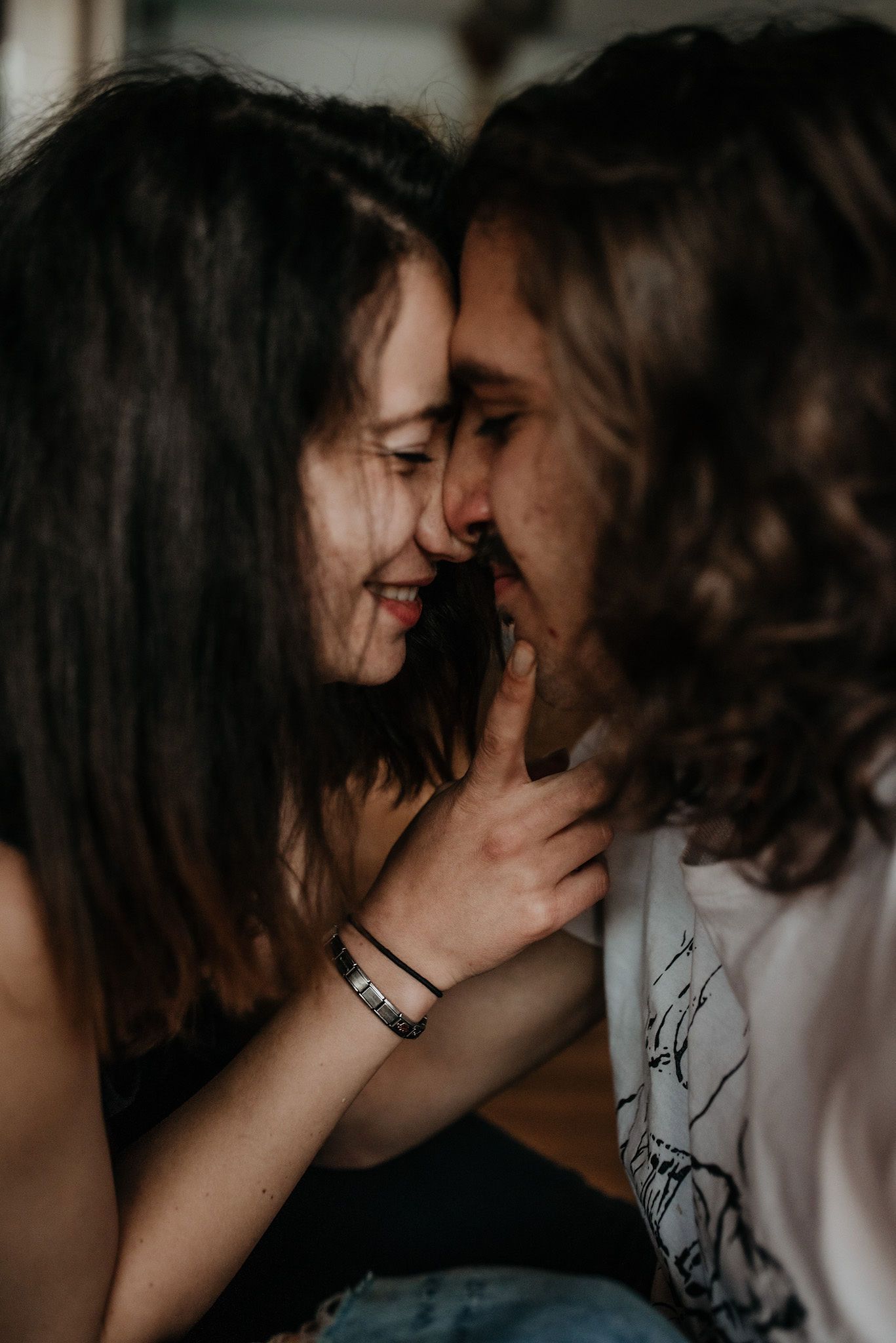 Two people share an intimate moment in a series of dimly lit close-up photos showing tender affection and connection.