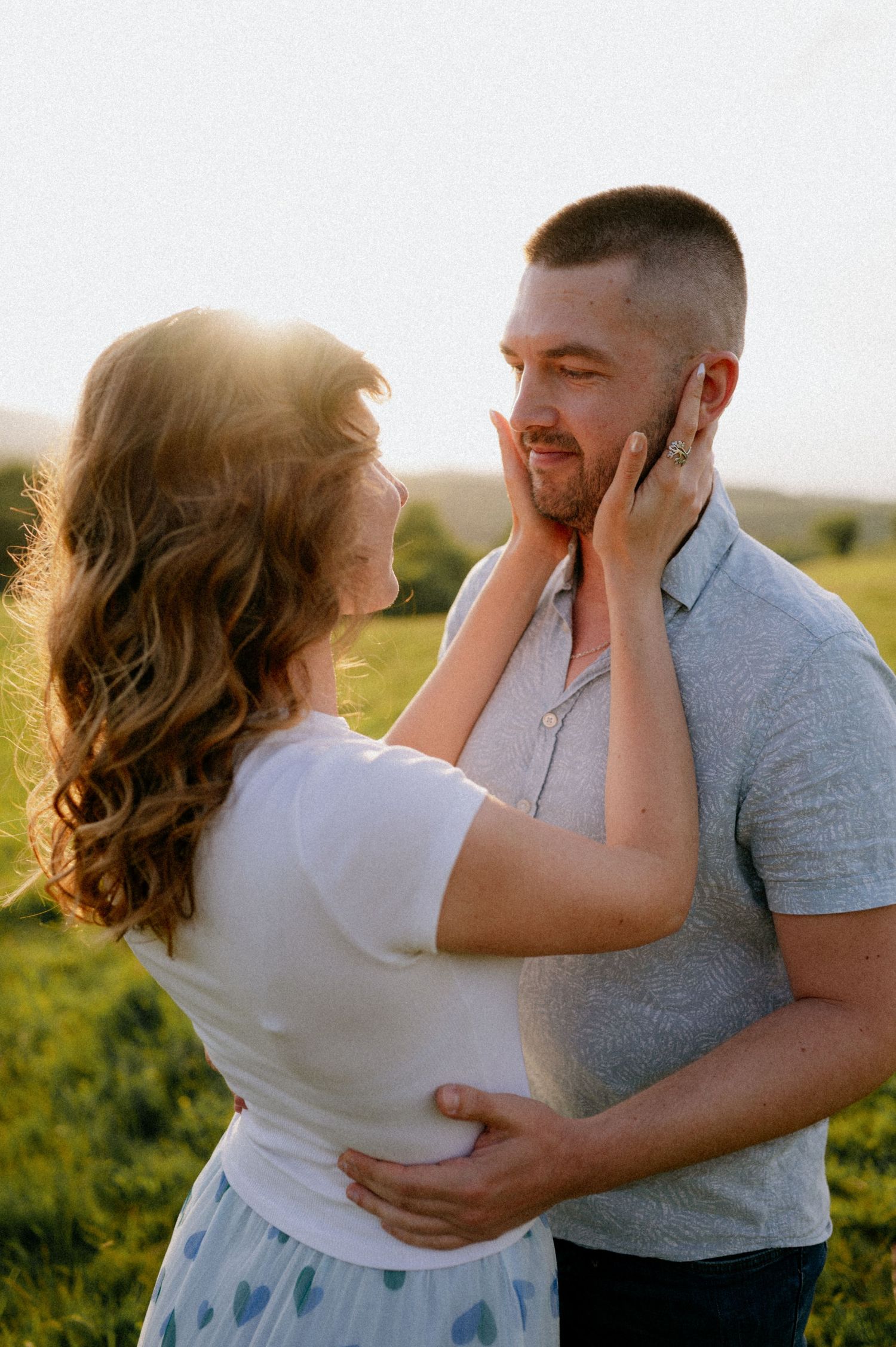 Two people share joyful laughter while embracing in a sunlit field.