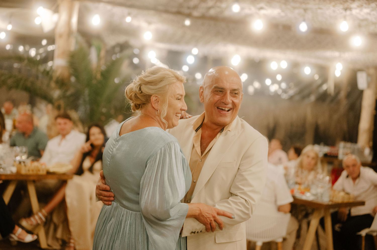 Guests celebrate at an elegant evening wedding reception with warm string lights creating a romantic ambiance.