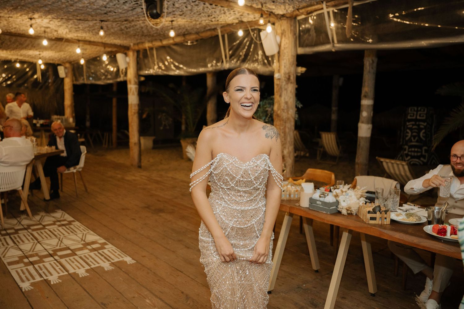 A rustic barn wedding reception venue decorated with string lights and wooden tables creating a warm, romantic atmosphere.