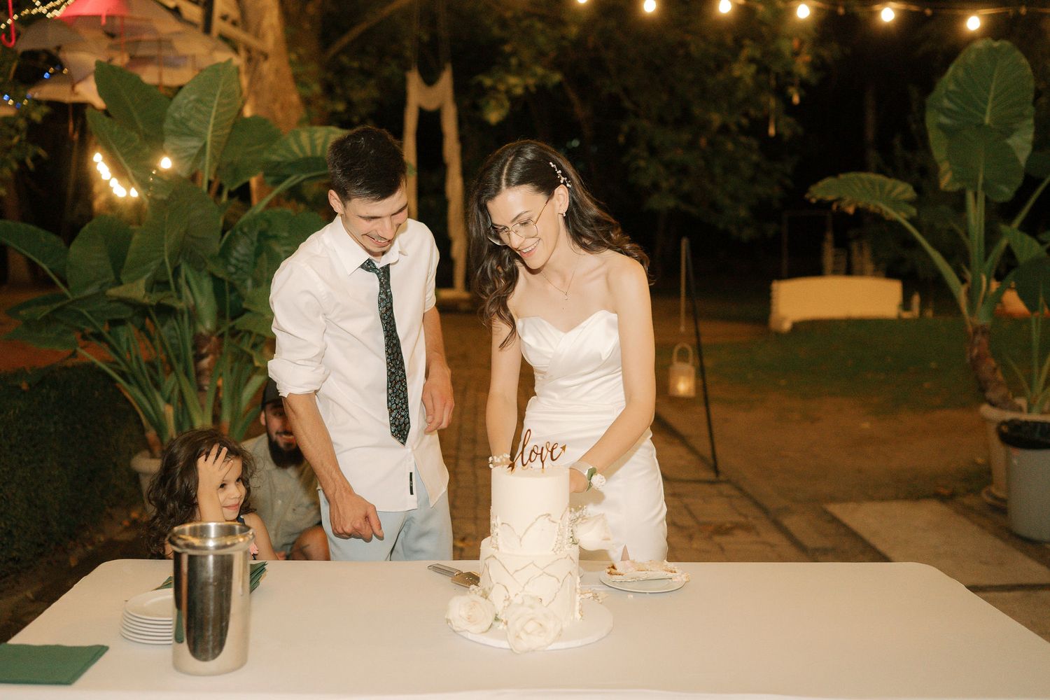 A series of wedding reception photos showing the couple cutting cake and enjoying an intimate outdoor evening celebration.