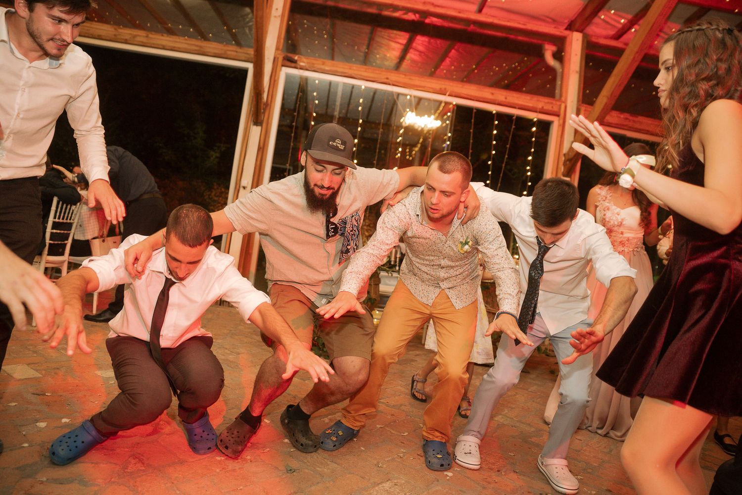 People perform the popular dance move known as the 'squat dance' at what appears to be a party or celebration.