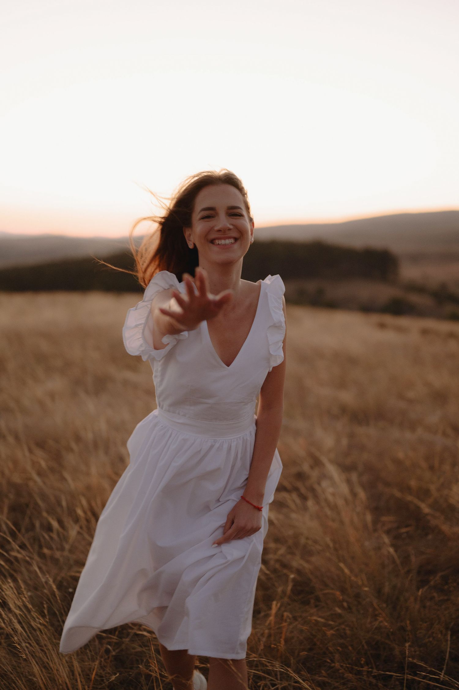 A person in a white dress spins joyfully in a golden field at sunset, creating a dreamy, ethereal scene.