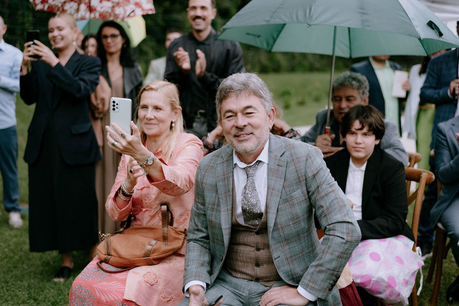 Wedding guests celebrate and dance together during an outdoor reception in a garden setting.