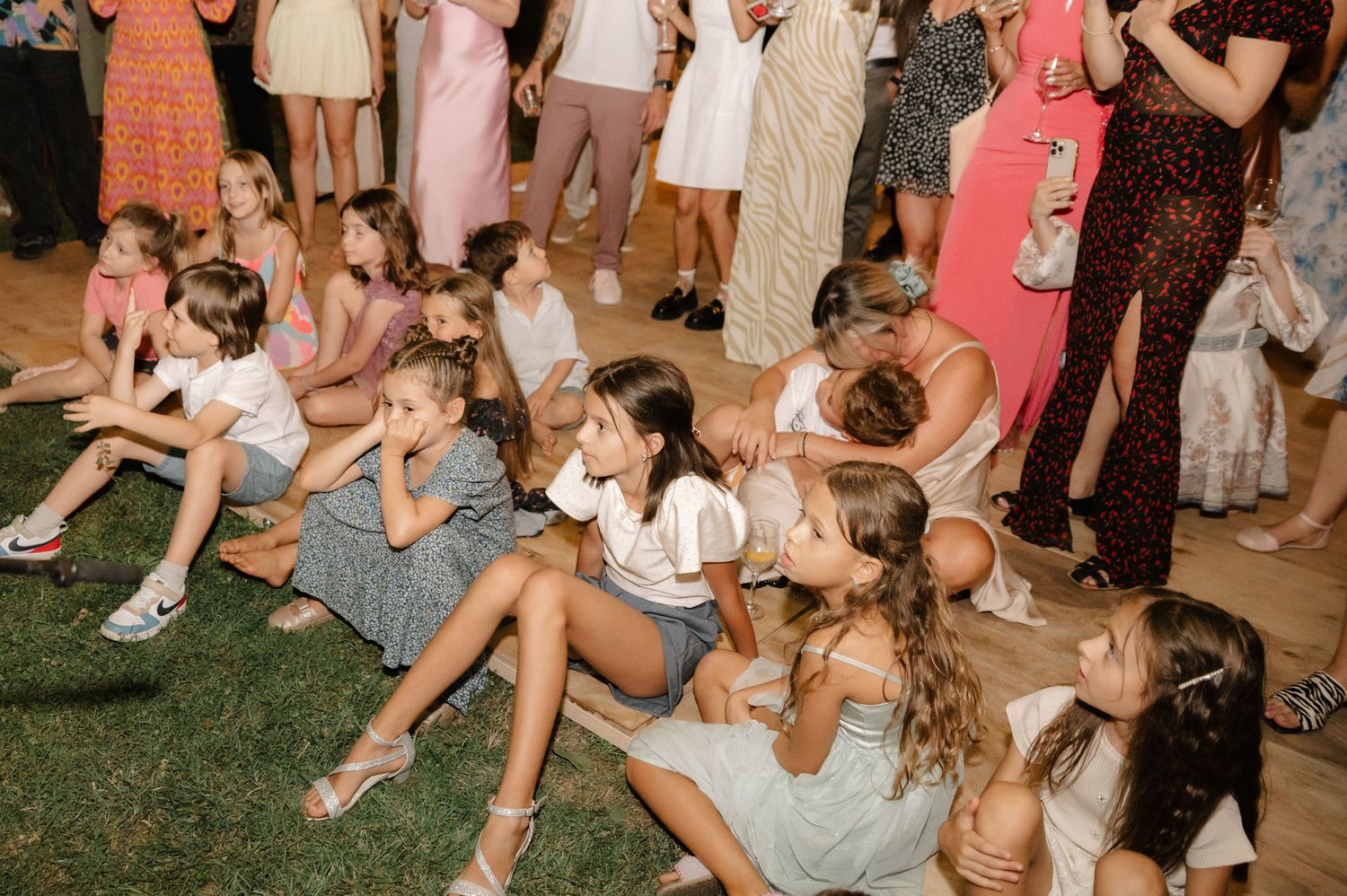 Wedding guests sitting on grass and socializing during an outdoor celebration.