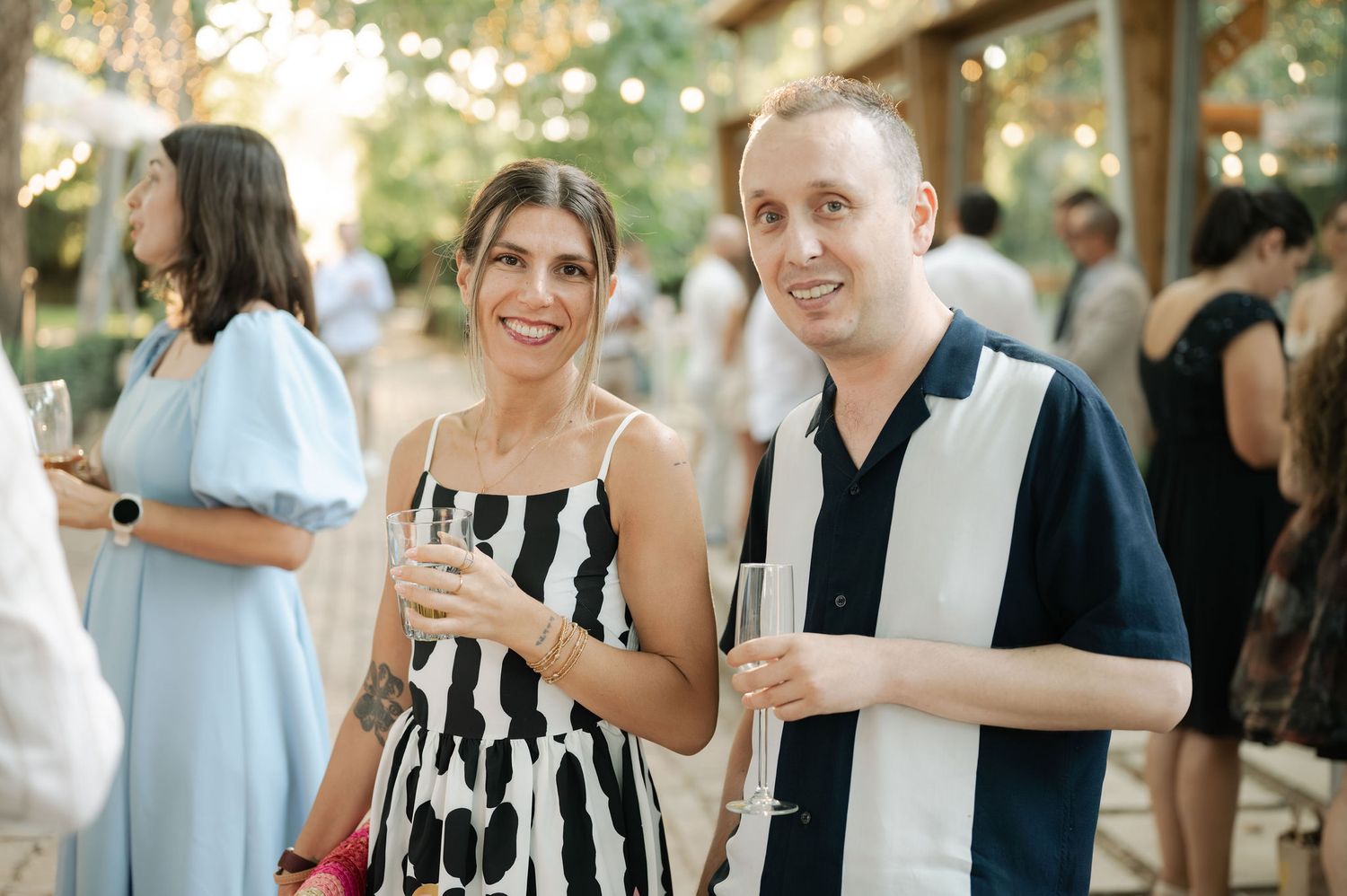 Wedding guests enjoying a casual outdoor reception with string lights and natural decor.