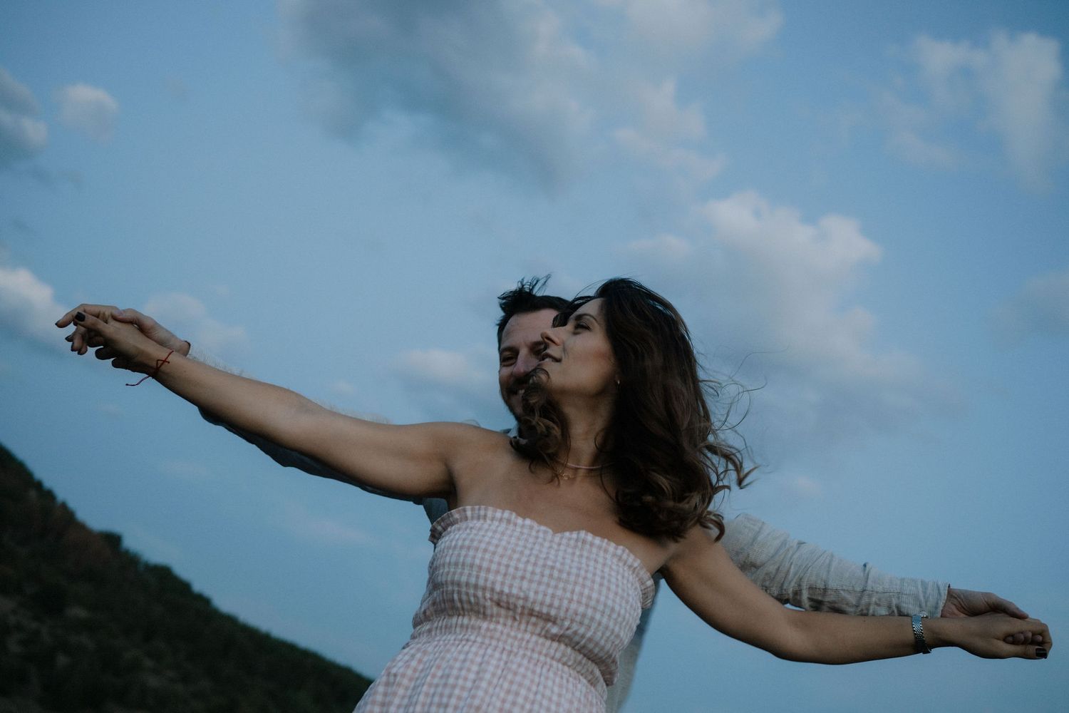 A person dances and performs on stage against a bright blue sky at an outdoor concert venue.