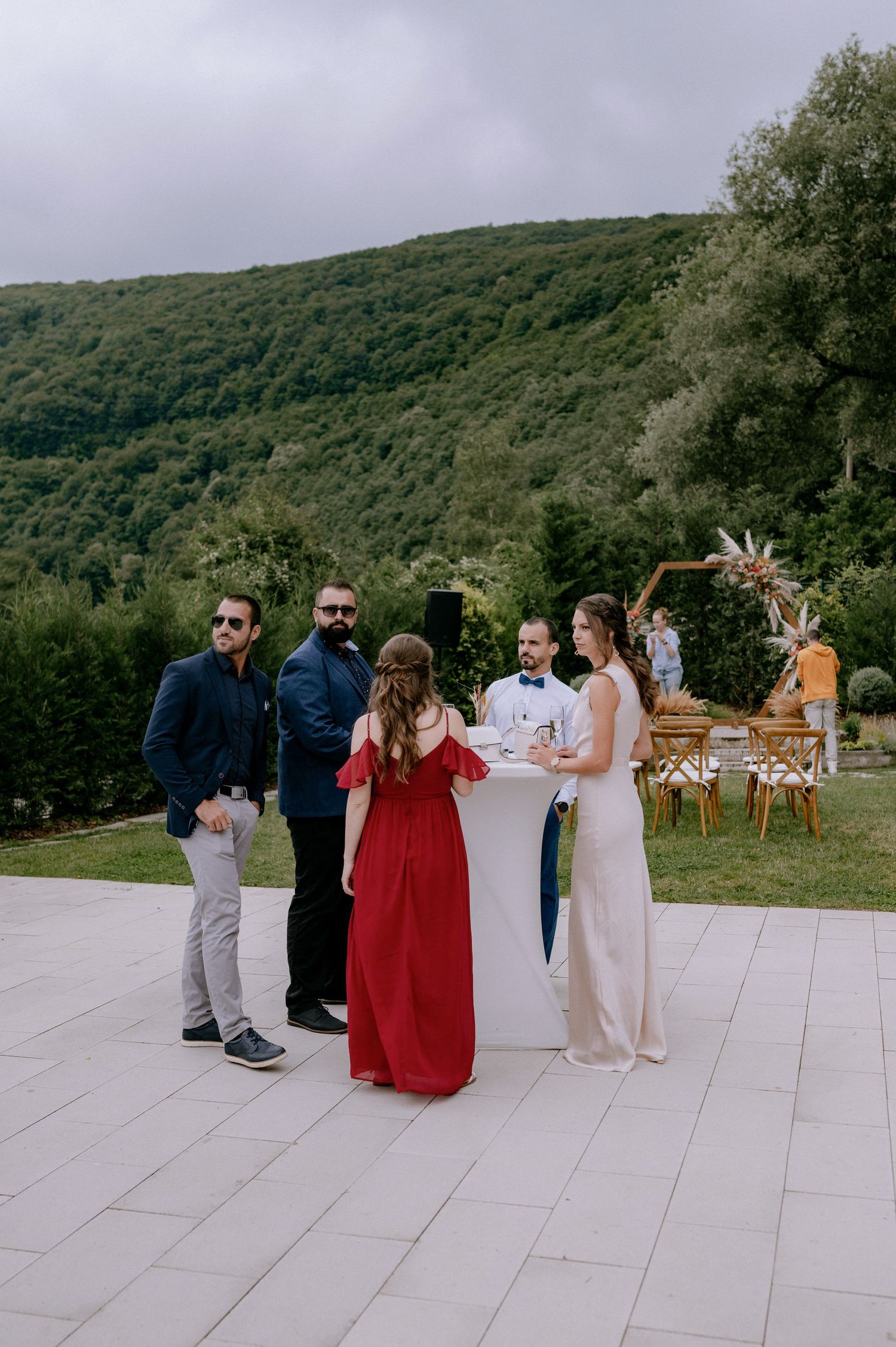 A group gathers on an outdoor dance floor with scenic mountain views and forest backdrop during a celebration event.