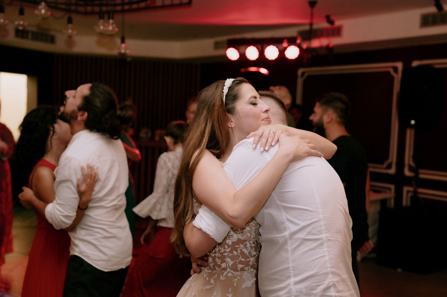 Couples dancing together under warm lighting at a festive evening celebration.