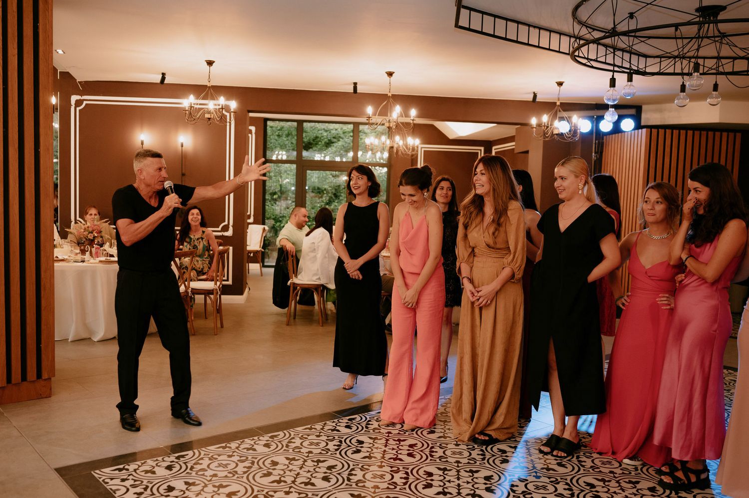 A photographer directs a group of people in formal attire during a wedding reception in an elegant venue.
