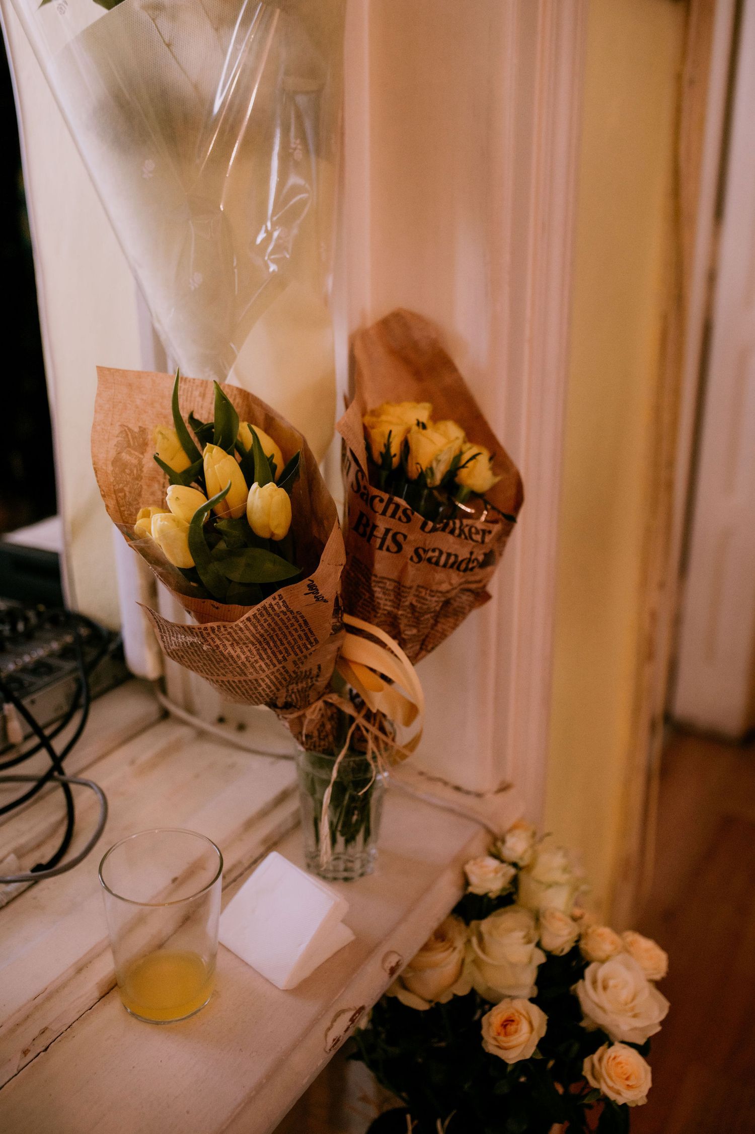 Fresh floral bouquets wrapped in brown paper sit on a windowsill with natural light streaming in.