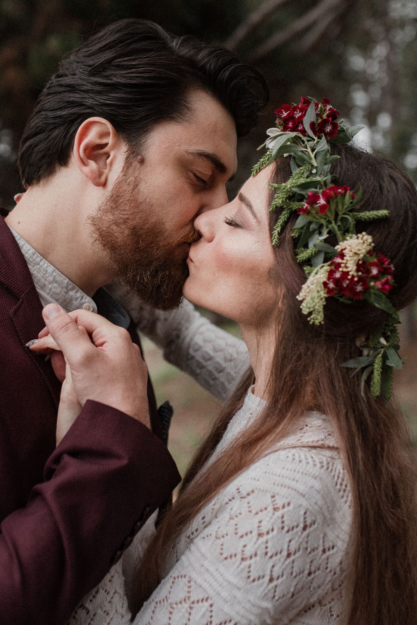 A romantic winter wedding moment captured in a series of intimate kisses against an evergreen backdrop.