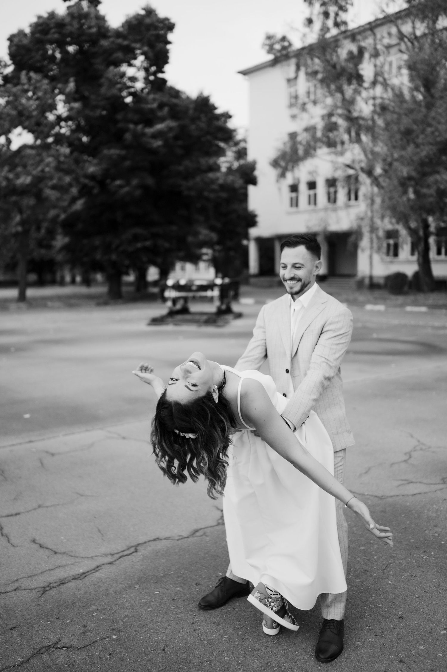 A romantic black and white photo series of a couple dancing and dipping in a parking lot.