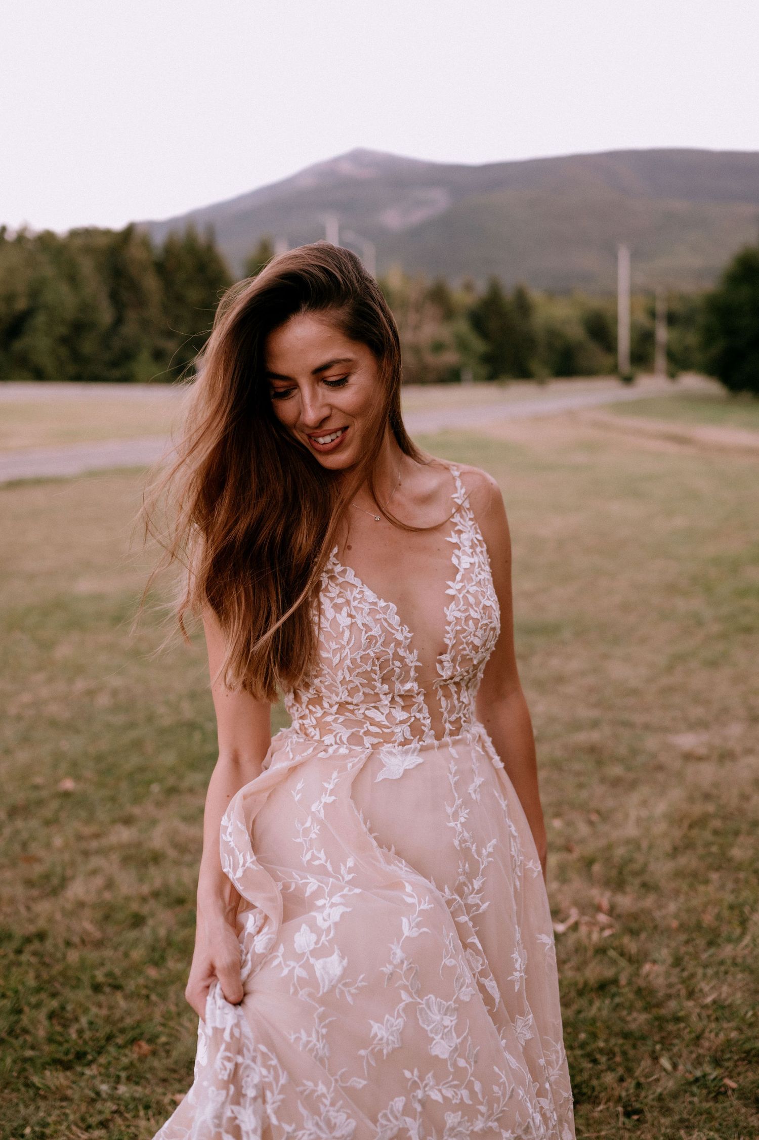 Ethereal bridal portrait featuring a sheer floral lace dress against a mountain backdrop.