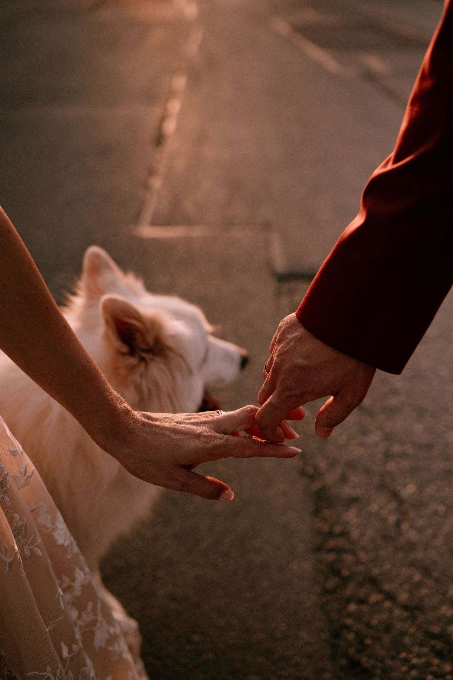 Close-up shot of hands reaching down to a white dress hem during golden hour.