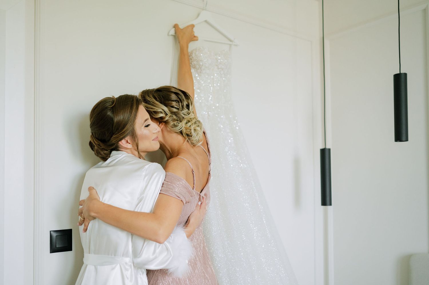 Wedding preparation scene showing dress adjustments in a bright interior.