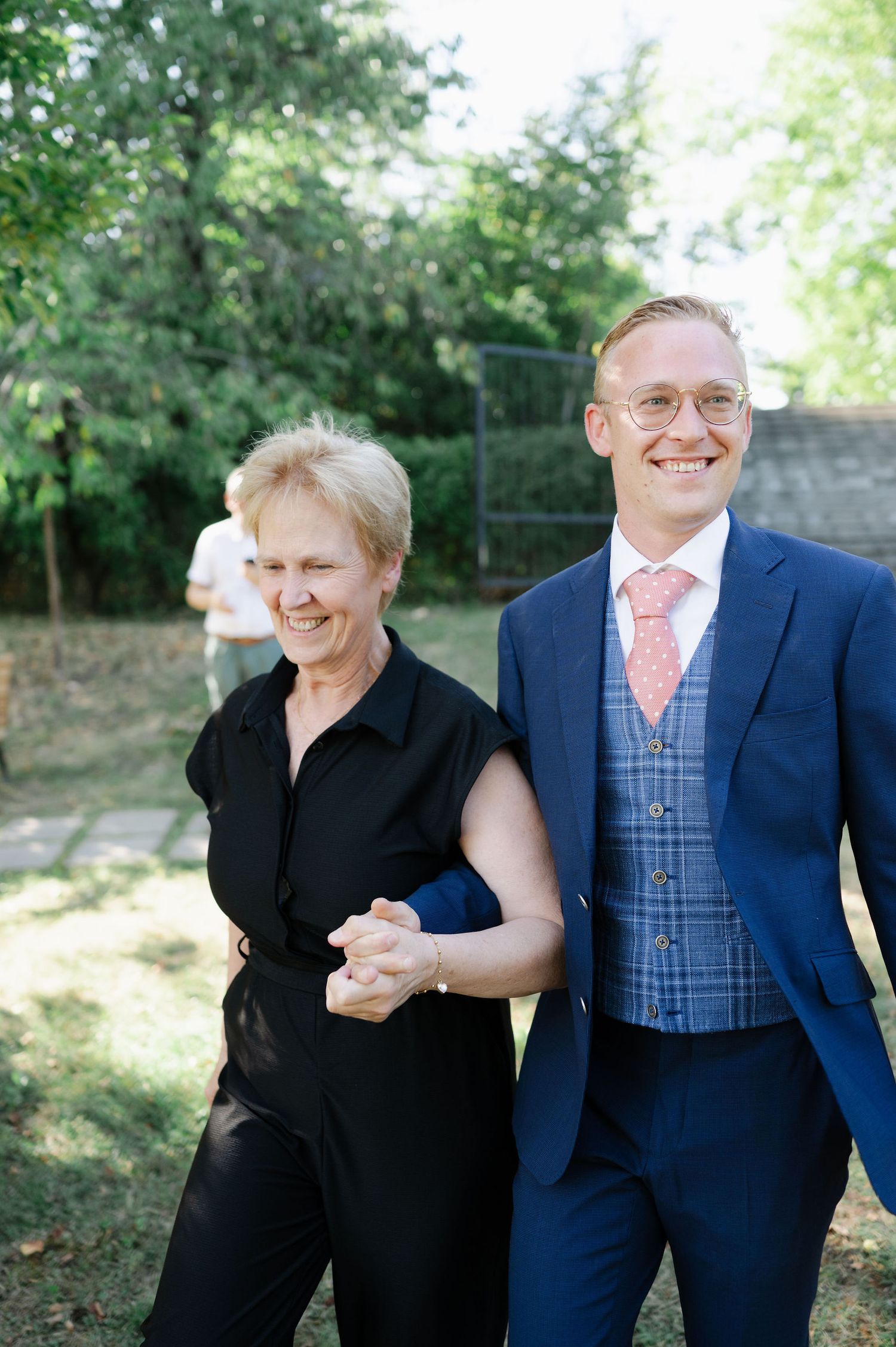 Joyful wedding party members pose together outdoors in formal attire.