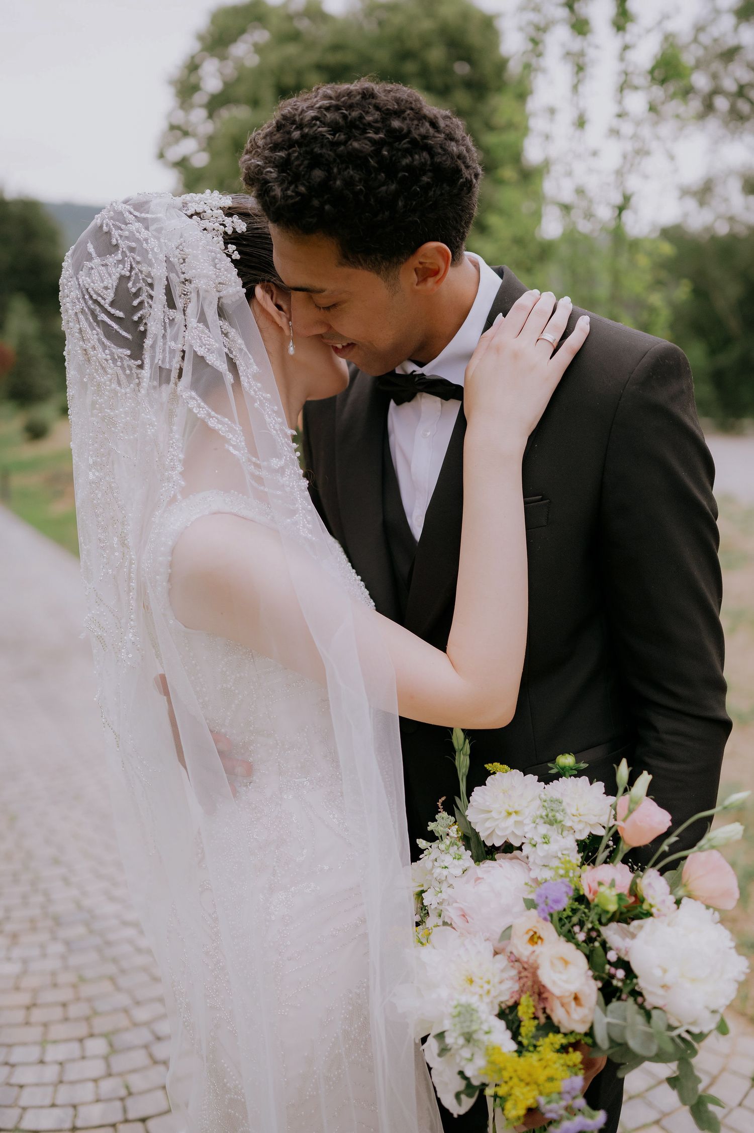 Intimate wedding portrait moment with delicate lace veil and white floral bouquet.