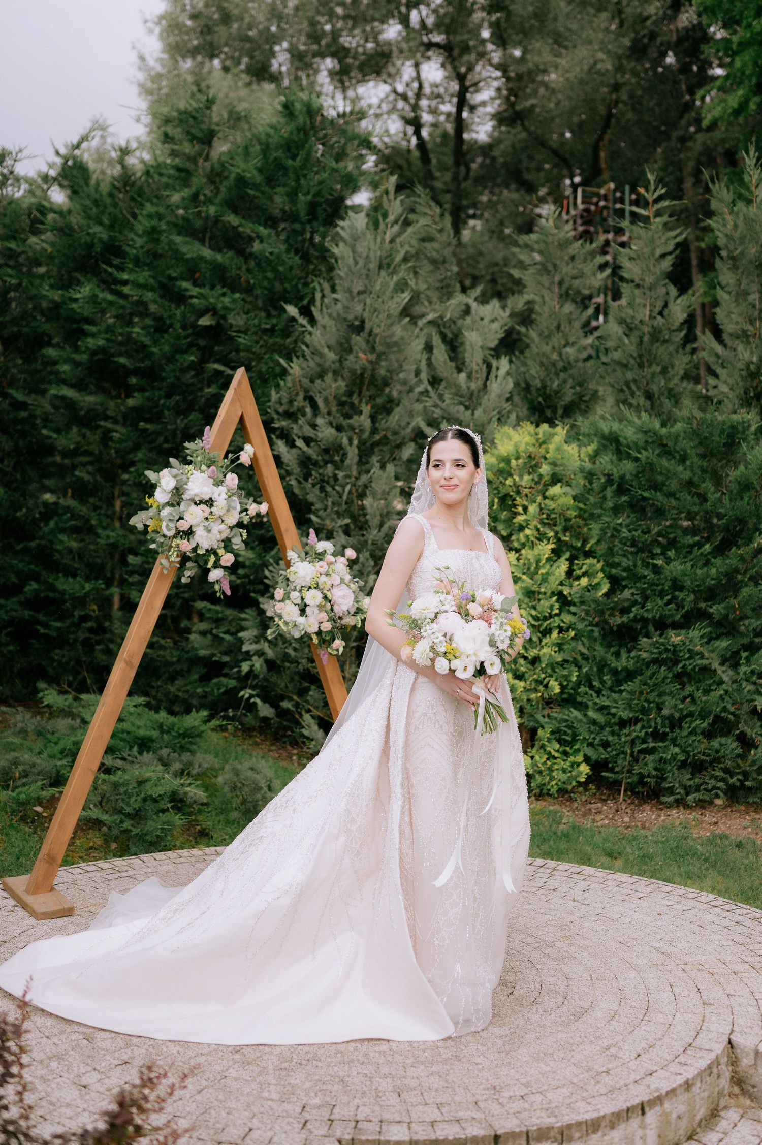 Bridal portrait session on circular stone patio surrounded by lush garden landscape.