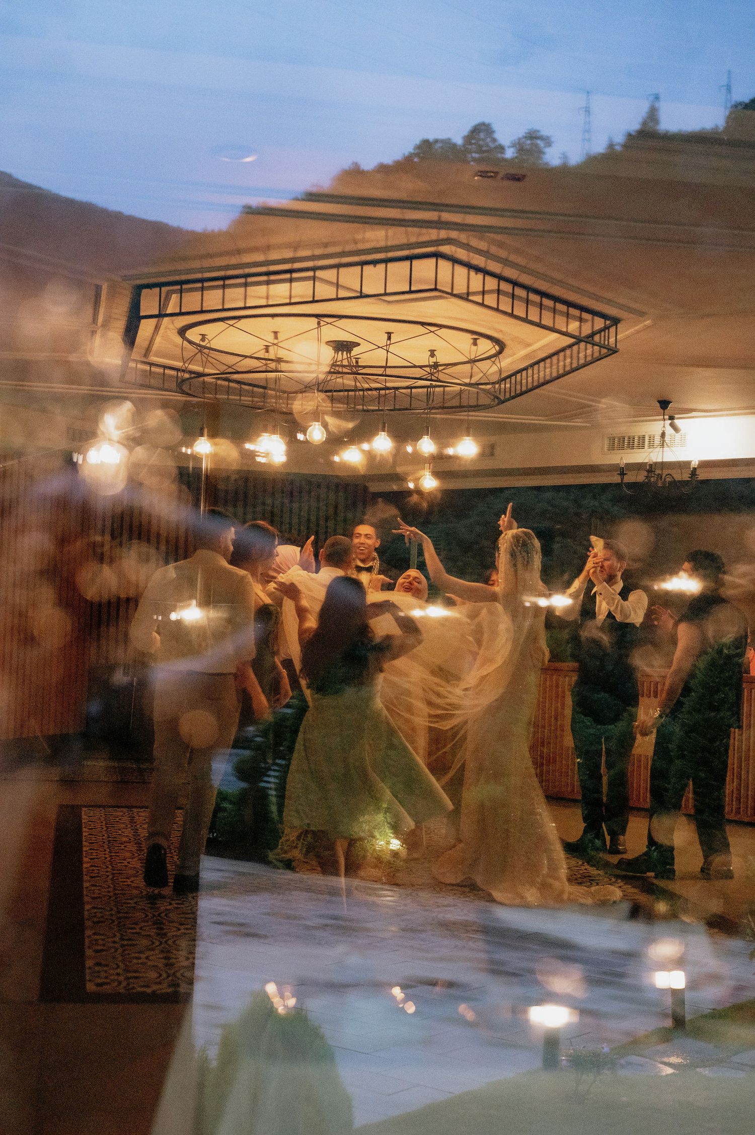 Multiple exposure photograph shows dancers moving across a dance floor under elegant ceiling lights.