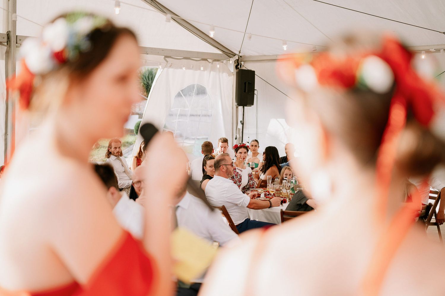 Blurred view of wedding guests seated at tables during reception.