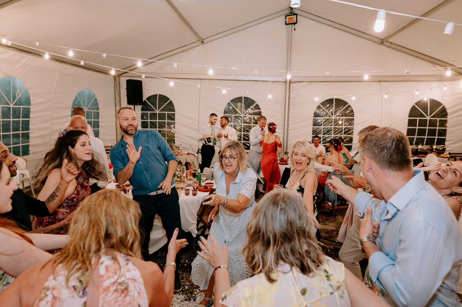 Wedding guests enjoy dancing and socializing at a lively tent reception.